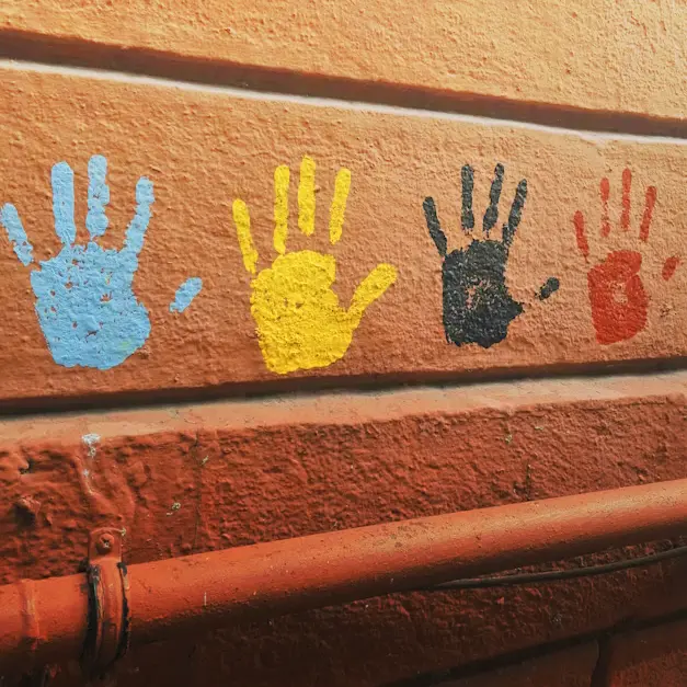Children painting handprints on a brick wall